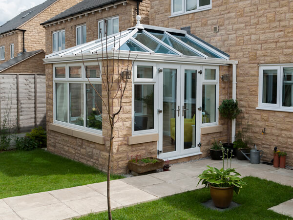 A white UPVC conservatory with brick elements